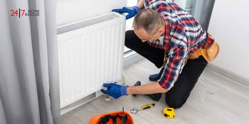 Why Is My Radiator Cold? – Common Faults and How to Fix Them Technician in work overalls using a wrench to repair a heating radiator in a room