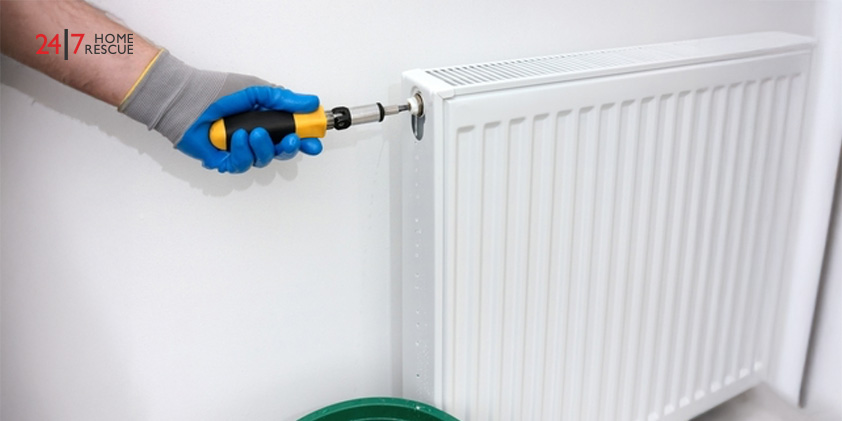 Why Is My Radiator Cold? – Common Faults and How to Fix Them Technician using a tool to release air and water from a radiator air bleed valve