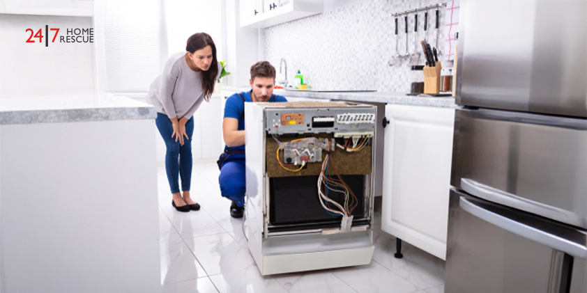 Dishwasher Not Filling with Water? Causes & Fixes Explained A smiling woman standing behind a technician repairing a dishwasher in the kitchen