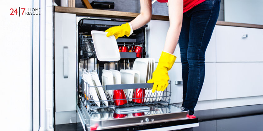 My dishwasher is not draining! Young woman taking out clean dishes from dishwasher machine