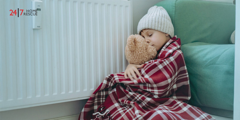 Boiler Switch On – Get Ready for the Winter Season A child staying cosy by the radiator, wrapped in a blanket and holding a teddy bear for extra warmth