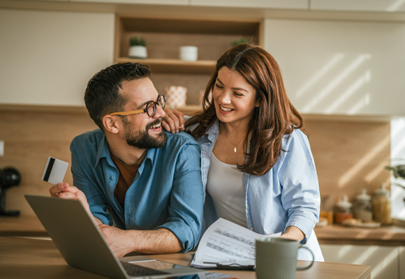 Smiling couple making an online payment with credit card to 24|7 Home Rescue