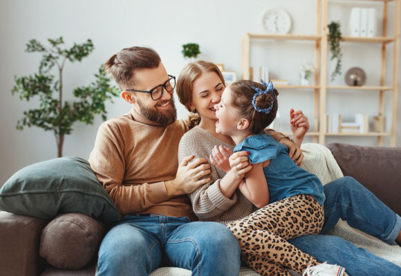 Family laughing together on a sofa at home