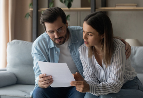 Couple reviewing a paper document together on a sofa - understanding boiler service costs in the UK