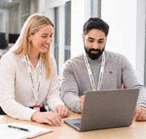 Two 24|7 Home Rescue colleagues wearing lanyards reviewing information together on a laptop