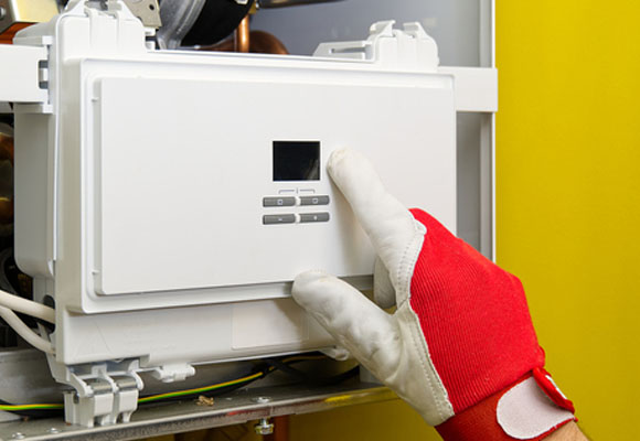 Gloved hand adjusting the control panel on a boiler unit curing boiler repair