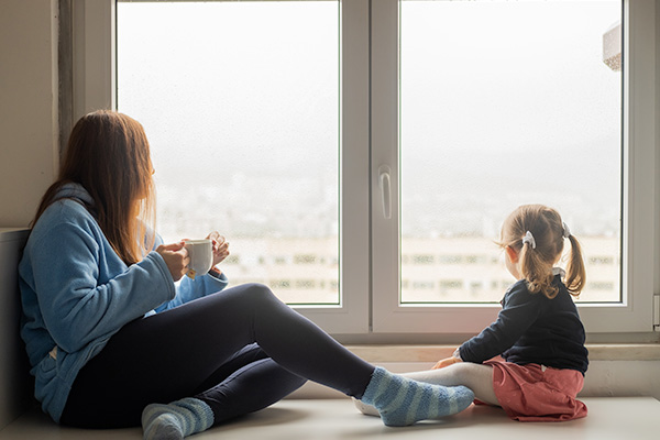 Woman relaxing on sofa with feet up near radiator in warm home