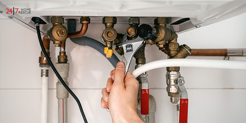 Hand holding wrench on boiler pipes