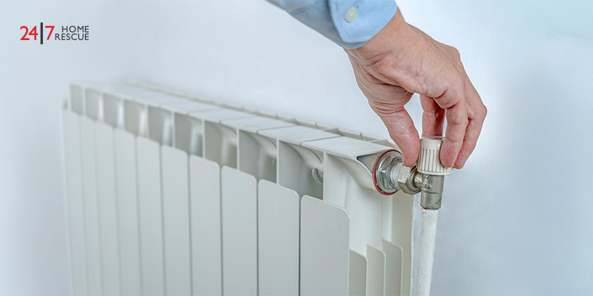 Hand turning radiator valve on white wall